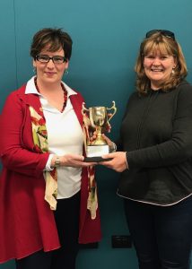 Laura Bruce holding the district 72 Toastmasters Humourous Speech Trophy, with Erin Daldry DTM